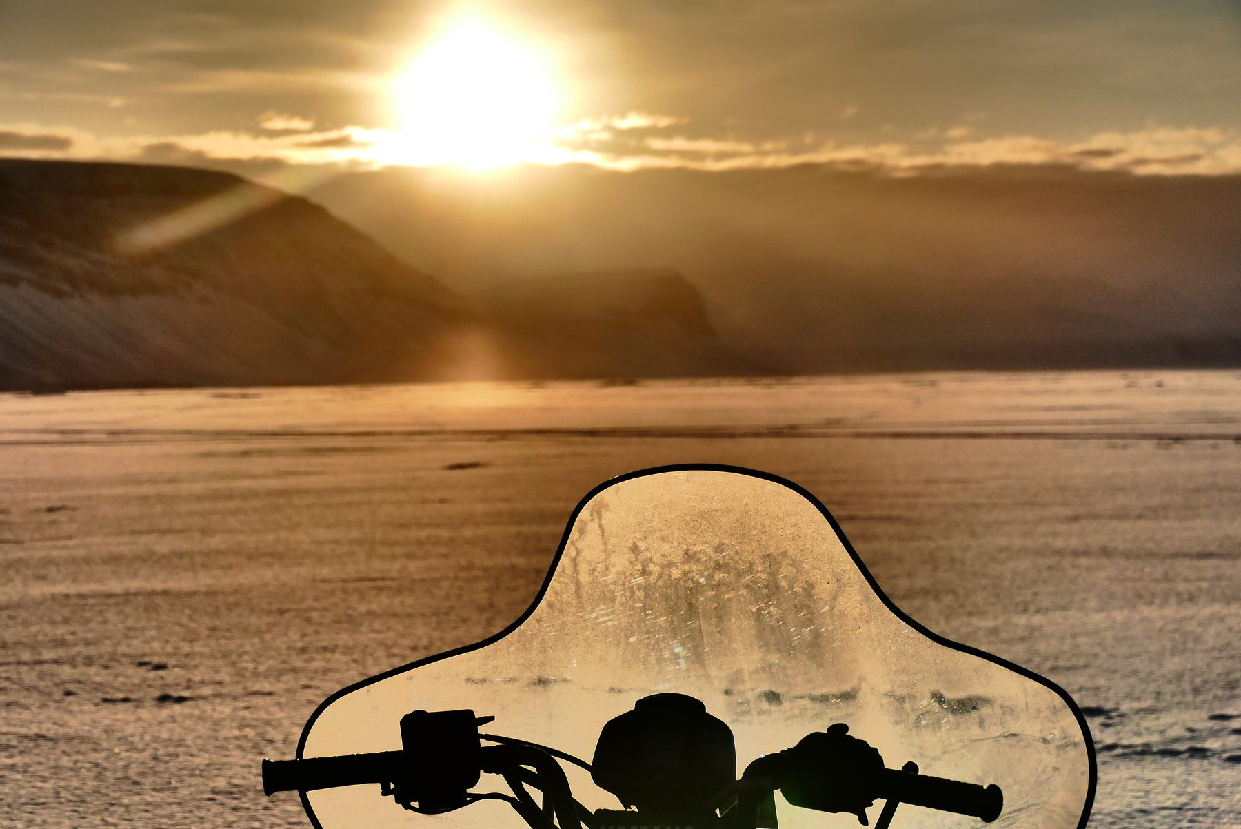The sun and a snow mobile on sea ice
